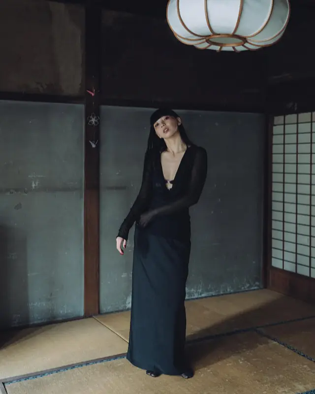 和室に立つ黒い衣装の人物